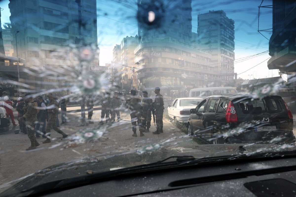 Lebanese army soldiers are seen through the bullet-riddled window of a car after deadly clashes erupted along a former 1975-90 civil war front-line between Muslim Shiite and Christian areas, in Ain el-Remaneh neighborhood, Beirut, Lebanon, Thursday, Oct. 14, 2021. Lebanese officials say at least six people were killed and dozens were wounded in armed clashes that erupted in Beirut during protests organized by the militant Hezbollah group and its allies against the lead investigator into last year’s massive blast at the city's port. (AP Photo/Bilal Hussein)