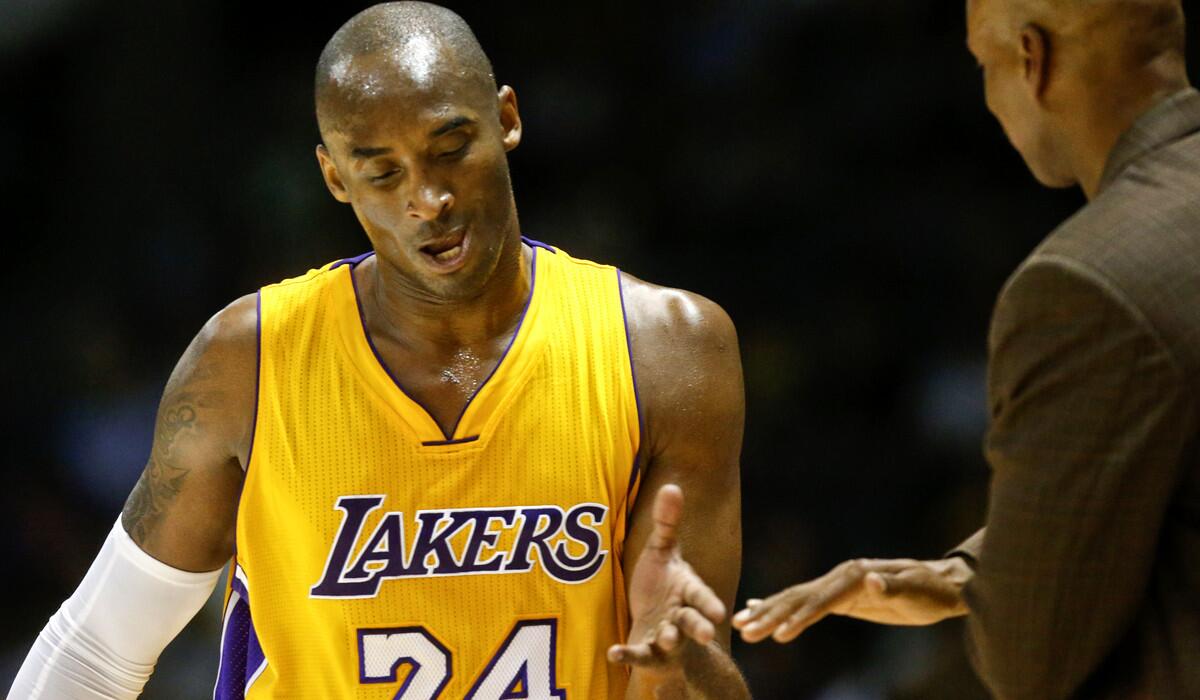 Lakers guard Kobe Bryant gets a hand slap from Coach Byron Scott after leaving the court against the Nuggets in an exhibition game Monday.