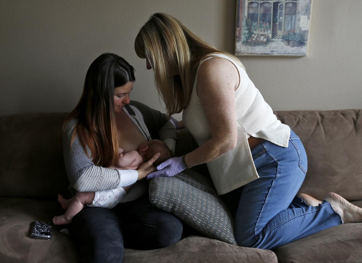 Lactation consultant Rachelle King, right, advises her client Kaitlyn Ramos during a home visit in Rancho Santa Margarita.