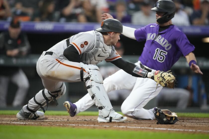 San Francisco Giants catcher Patrick Bailey, front, fields the throw as Colorado Rockies' Randal Grichuk scores from third base on a ground ball hit by Nolan Jones in the fourth inning of a baseball game Tuesday, June 6, 2023, in Denver. (AP Photo/David Zalubowski)