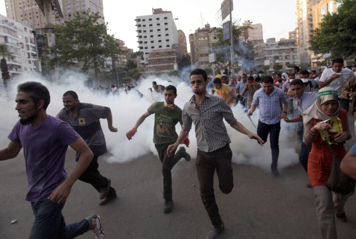 Supporters of Egypt's ousted President Mohamed Morsi run for cover from tear gas fired by police, not seen, on Aug. 30 during a protest in Cairo. Four police officers face arrest for the deaths of protesters who were allegedly tear-gassed inside a police van.