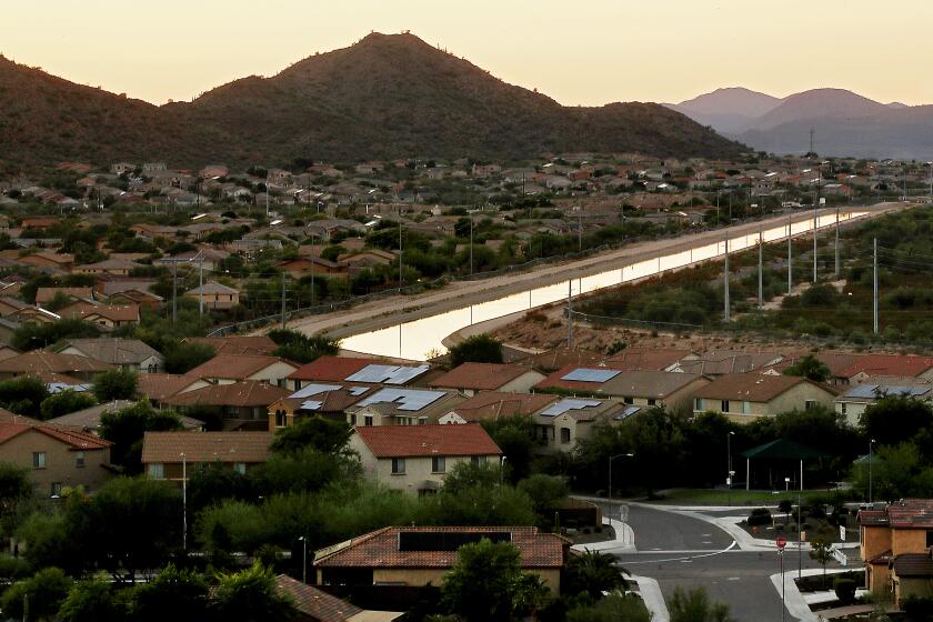 BUCKEYE, ARIZONA OCT. 10, 2022. The Central Arizona Project Canal runs beside a community in the suburbs of North Phoenix. Development projects envisioning thousands of new homes around Phoenix now are in question because of lack of water. Dwindling Colorado River water is delivered to Central Arizona, one of the fastest growing metropolitan areas in the U.S., via the Central Arizona Project Canal. River flows are at historic lows due to warmer and drier conditions caused by climate change. (Luis Sinco / Los Angeles Times)