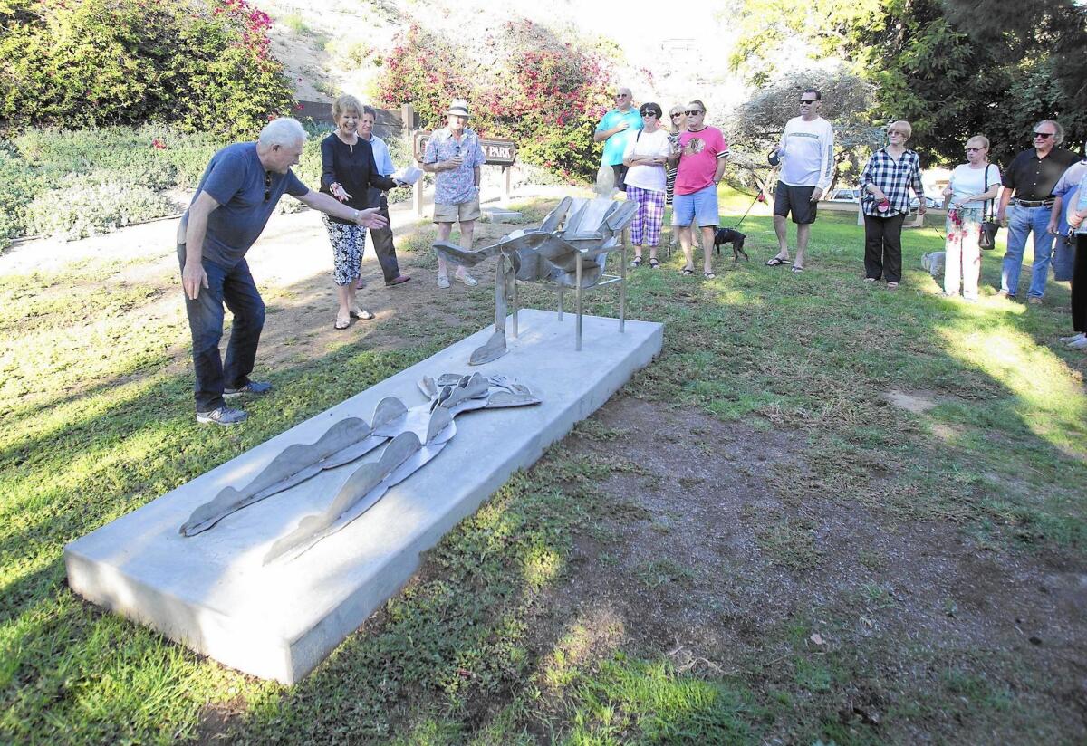 Artist Leonard Glasser, left, talks about the new “Sunbathers” public art sculpture as Laguna Arts Commissioner Pat Kolenda looks on with others during a commemoration ceremony at Rita Carman Park in Laguna Beach.