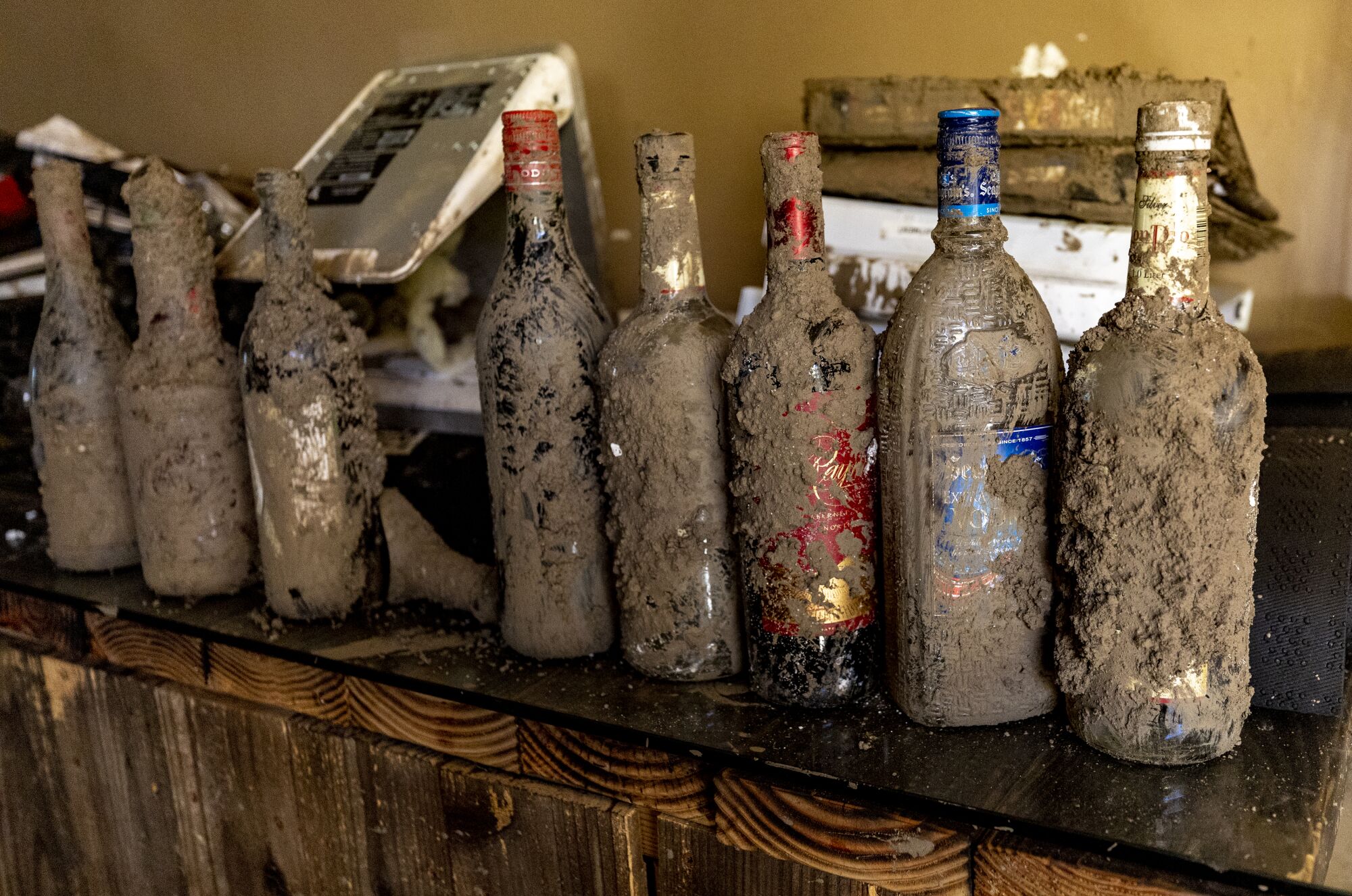 A row of alcohol bottles caked in mud
