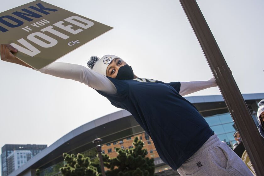 Eylia Love, of the Georgia Tech Womens basketball team, holds a voting sign outside of McCamish Pavillion.