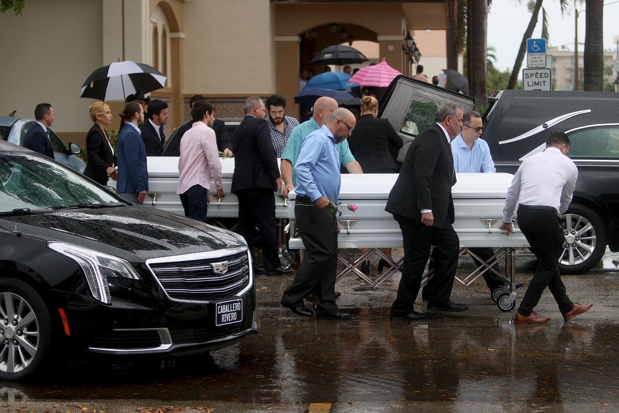 Pallbearers bring caskets to the hearse after the funeral at St. Joseph Catholic Church.