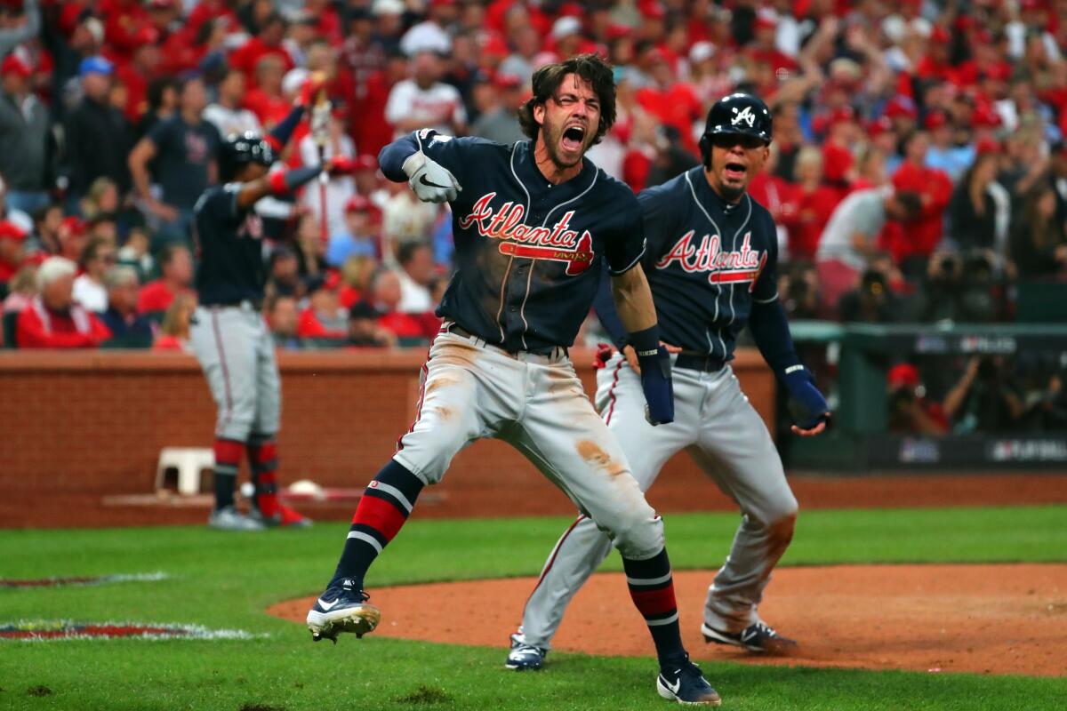 Atlanta's Dansby Swanson, left, and Rafael Ortega celebrate after scoring on a single from Adam Duvall in the ninth inning during the Braves' 3-1 victory Sunday.