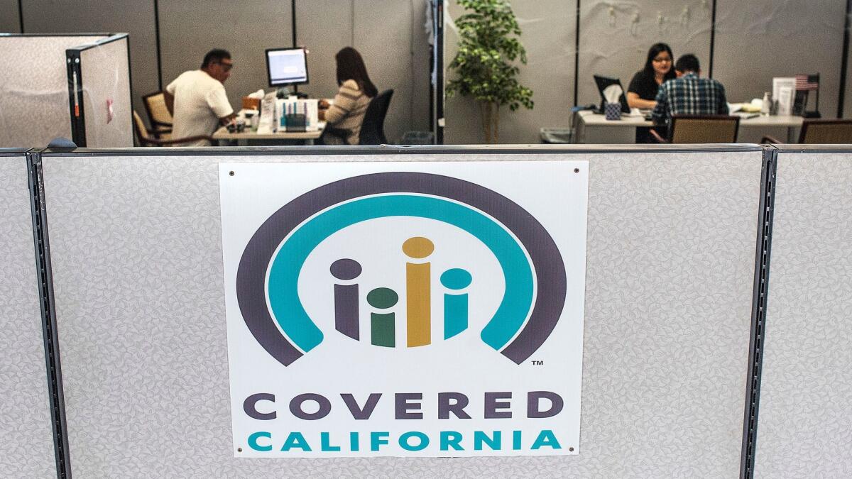 Insurance agents help sign people up for insurance through the Covered California exchange at a storefront in Huntington Beach.