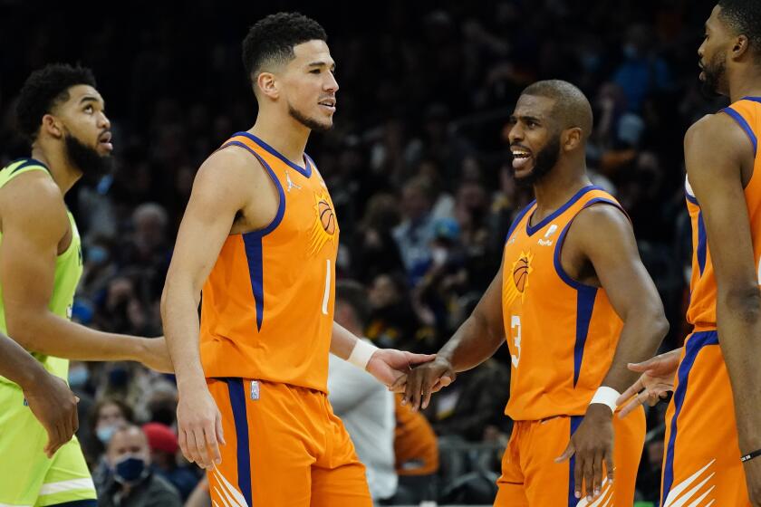 Phoenix Suns guard Devin Booker (1) and guard Chris Paul (3) celebrates against the Minnesota Timberwolves during the second half of an NBA basketball game, Friday, Jan. 28, 2022, in Phoenix. The Suns defeated the Timberwolves 134-124. (AP Photo/Matt York)