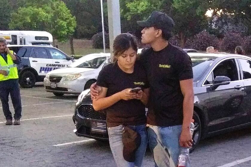 A young couple embrace at a parking lot after a shooting at the Gilroy Garlic Festival in Gilroy, Calif., Sunday, July 28, 2019. Several people were hospitalized Sunday after the shooting at the annual food festival in Northern California, a hospital spokeswoman said. (AP Photo/Thomas Mendoza)