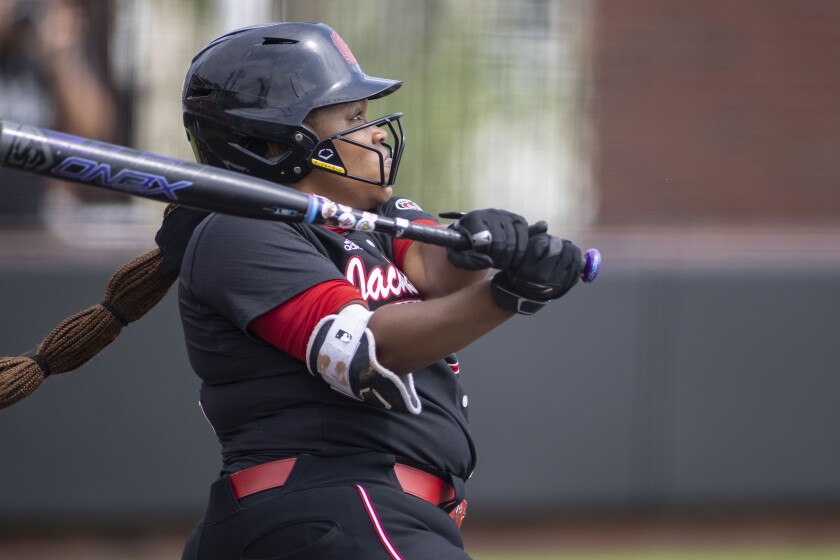 A softball player follows through on a swing.