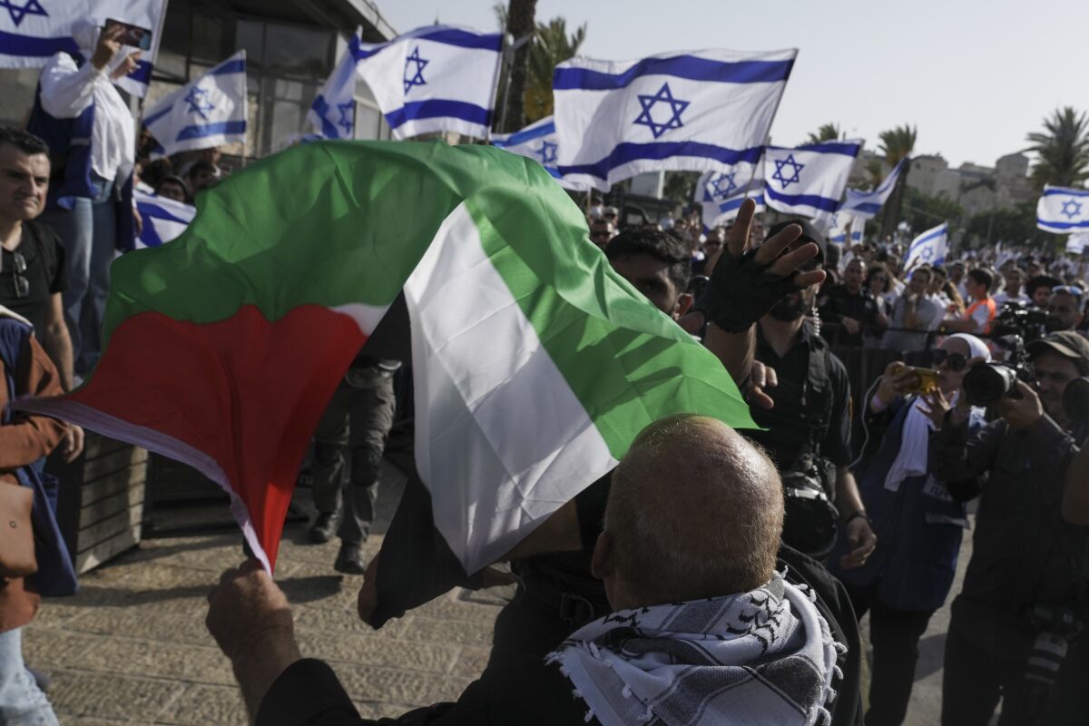 A man waving a Palestinian flag in front of a group of people waving Israeli flags