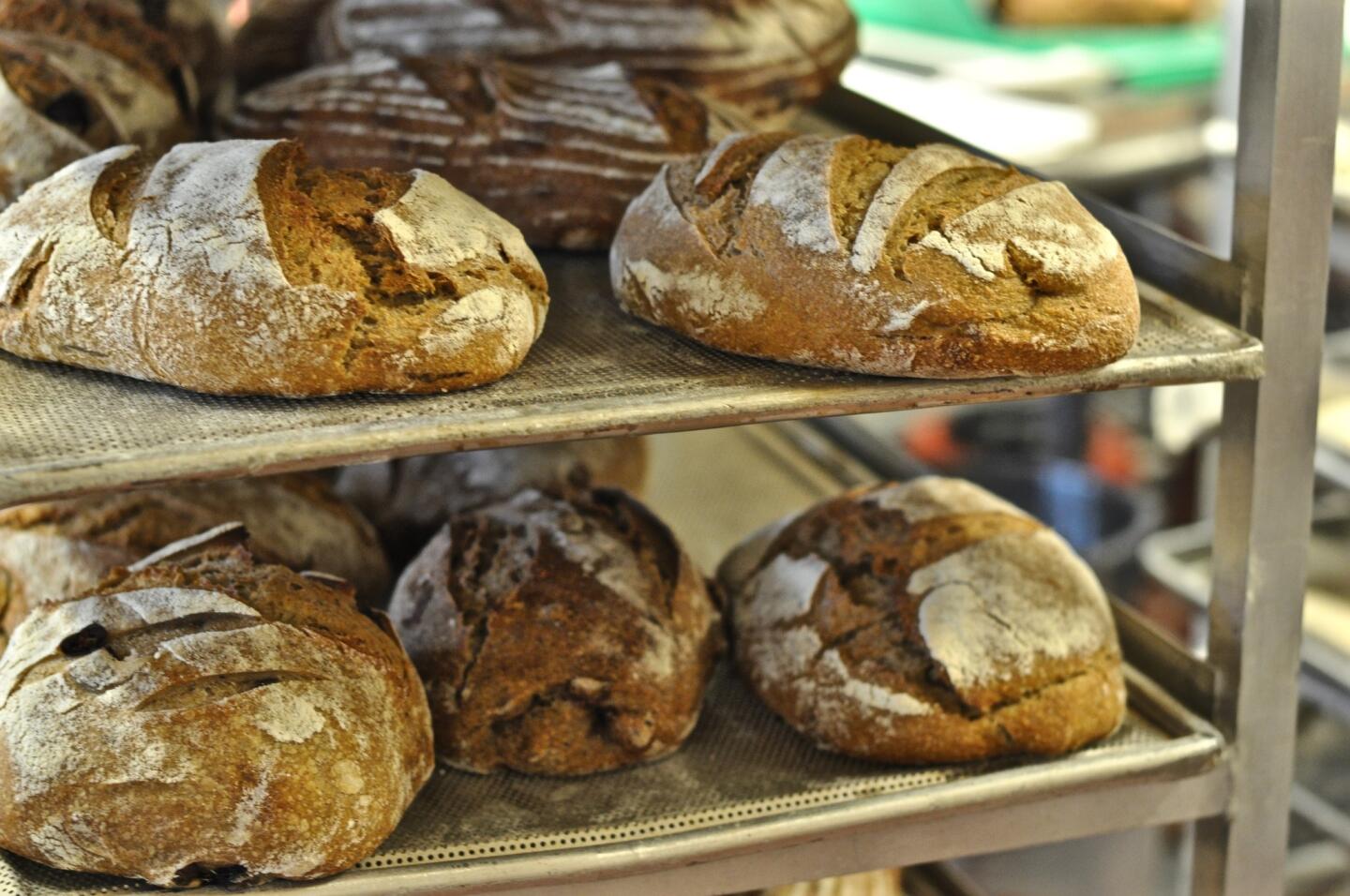 Loaves of whole grain bread rest in the kitchen near the deck oven at Seed Bakery in Pasadena.