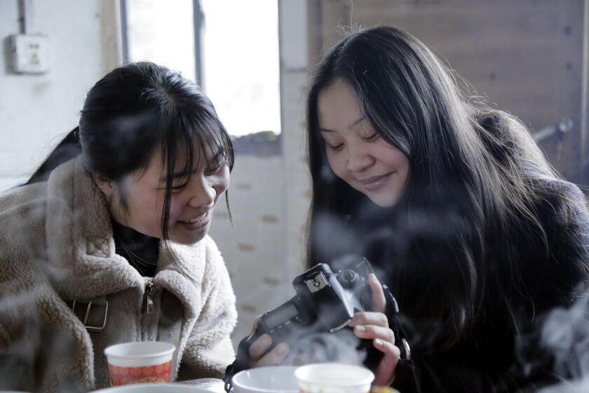 Esther shows Shuangjie photos she took with her camera. (credit to Liu Hongbin)