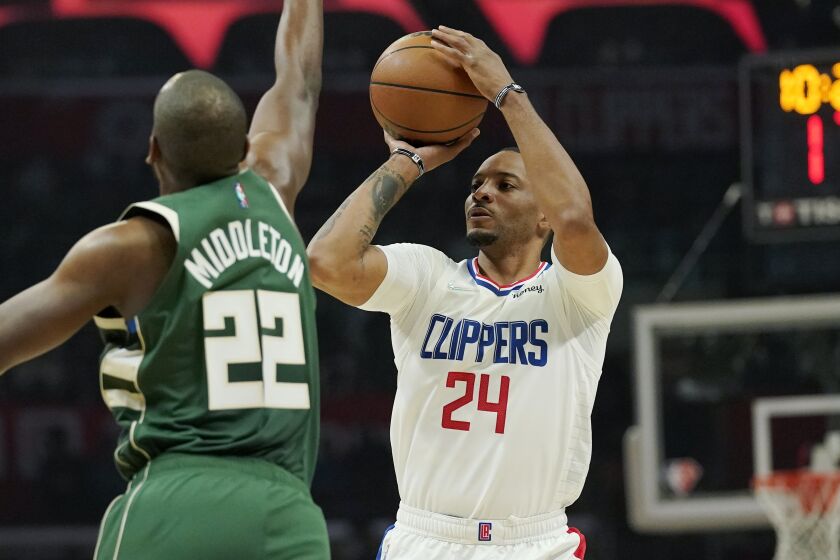 Los Angeles Clippers forward Norman Powell, right, shoots as Milwaukee Bucks forward Khris Middleton.