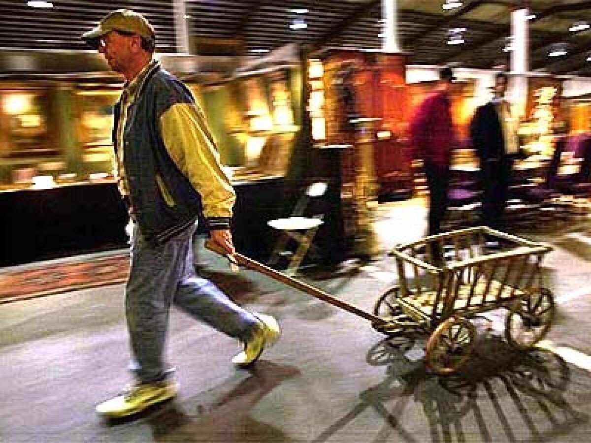 A customer rolls away a 100-year-old German cart, purchased for $250 from the stall of a Utah dealer.