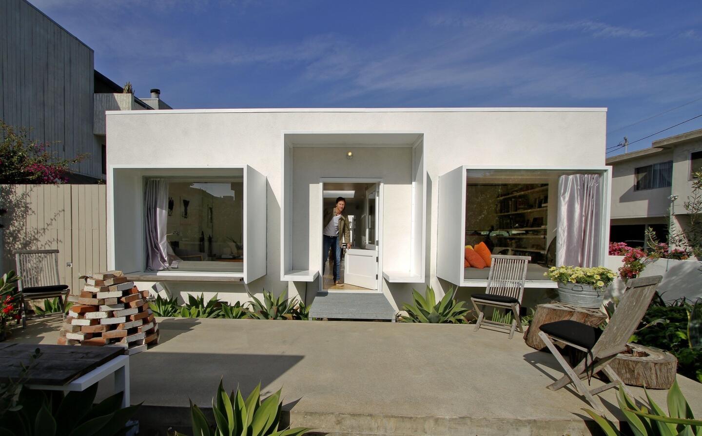 John Frane peeks out the entrance of his house, where he boxed the windows and door of what had been a Spanish-ized bungalow. The window boxes create built-in seating in the two front rooms. For a peek inside, keep clicking.