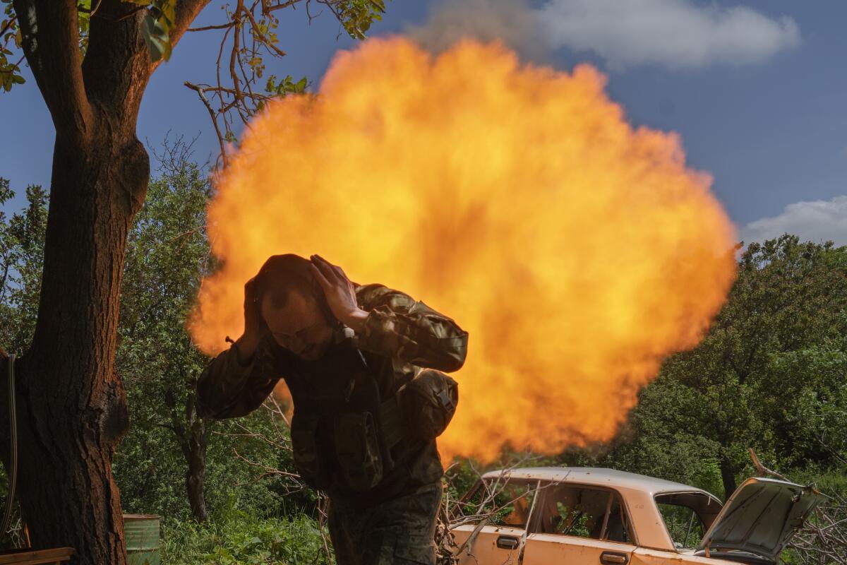A Ukrainian soldier covers his ears while firing a mortar at Russian positions near Bakhmut.