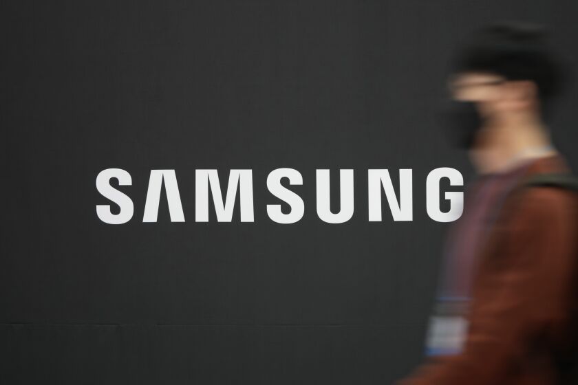 FILE - A visitor walks near the logo of Samsung Electronics in Seoul, South Korea, on Oct. 28, 2021. Samsung Electronics says its profit for the last quarter plummeted nearly 70% as a weak global economy depressed demands for its consumer electronics products and computer memory chips. (AP Photo/Lee Jin-man, File)