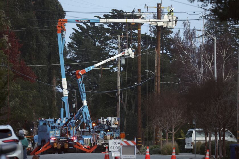 PG&E workers toil in the evening above Highland Avenue to replace equipment damaged by high winds in Santa Cruz, Calif., Tuesday, Jan. 10, 2023. (Shmuel Thaler/The Santa Cruz Sentinel via AP)
