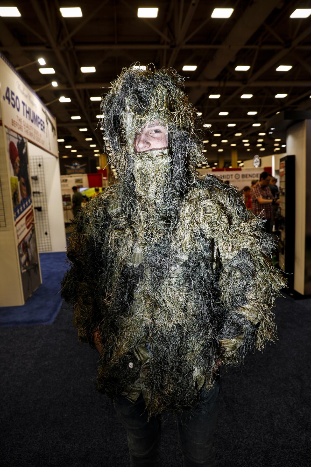 John Mikesell, 16, of Pittsburgh wears a ghillie suit, often used during hunting, while walking around the exhibition floor at the NRA meeting in Dallas.