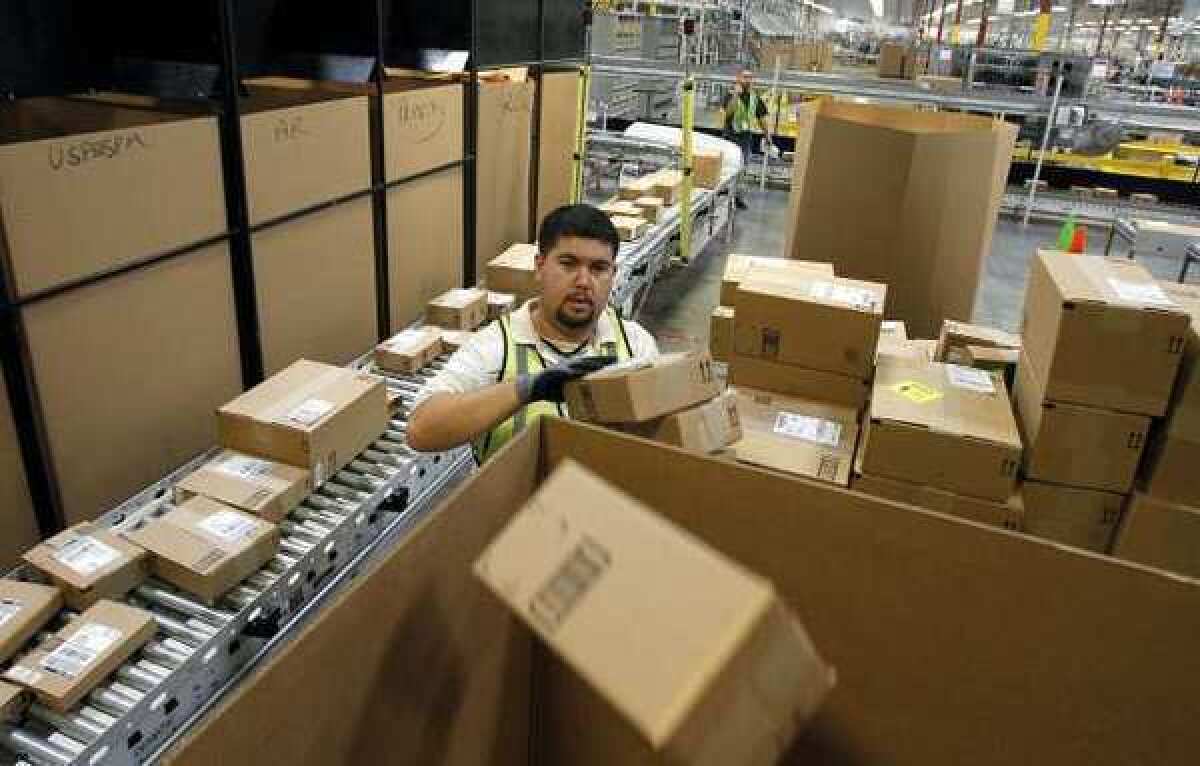 An Amazon worker places packages in the right shipping boxes at an Amazon.com fulfillment center in Phoenix.