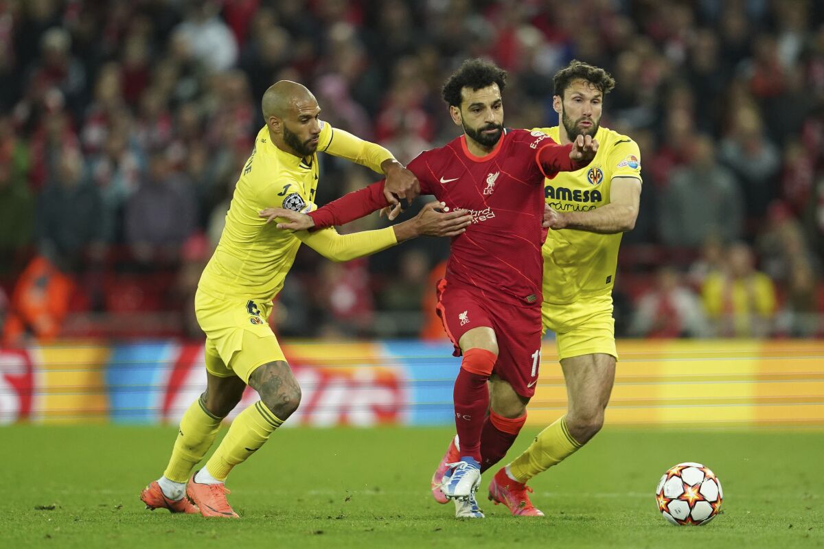 Liverpool's Mohamed Salah, center, fights for the ball with Villarreal's Etienne Capoue, left, Villarreal's Alfonso Pedraza during the Champions League semi final, first leg soccer match between Liverpool and Villarreal at Anfield stadium in Liverpool, England, Wednesday, April 27, 2022. (AP Photo/Jon Super)