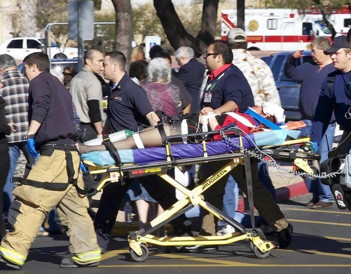 Emergency personnel and Daniel Hernandez, an intern for Rep. Gabrielle Giffords, second right, move Giffords after she was shot in the head outside a shopping center in Tucson, Ariz. on Jan. 8, 2011.