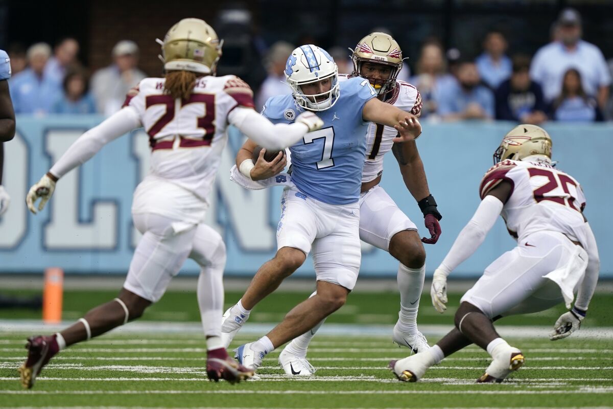 North Carolina quarterback Sam Howell (7) runs with the ball while Florida State defensive back Sidney Williams (23), linebacker Kalen DeLoach (20) and defensive end Jermaine Johnson II, rear, look to tackle him during the first half of an NCAA college football game in Chapel Hill, N.C., Saturday, Oct. 9, 2021. (AP Photo/Gerry Broome)