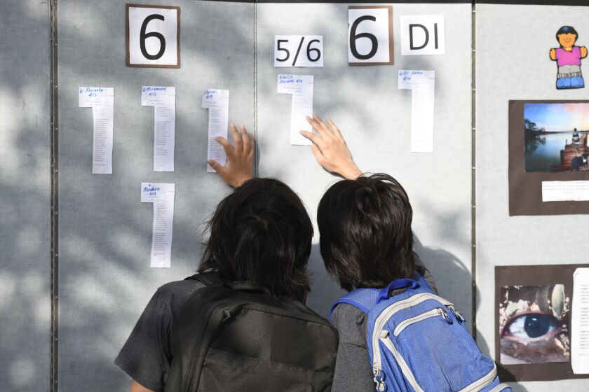 Parents and students look at the class list on the first day of school at Enrique S. Camarena Elementary School Wednesday, July 21, 2021, in Chula Vista, Calif. The school is among the first in the state to start the 2021-22 school year with full-day, in-person learning. (AP Photo/Denis Poroy)