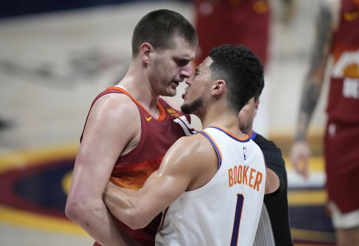 El pívot de los Nuggets de Denver, Nikola Jokic (izquierda) discute con el base de los Suns de Phoenix Devin Booker.
