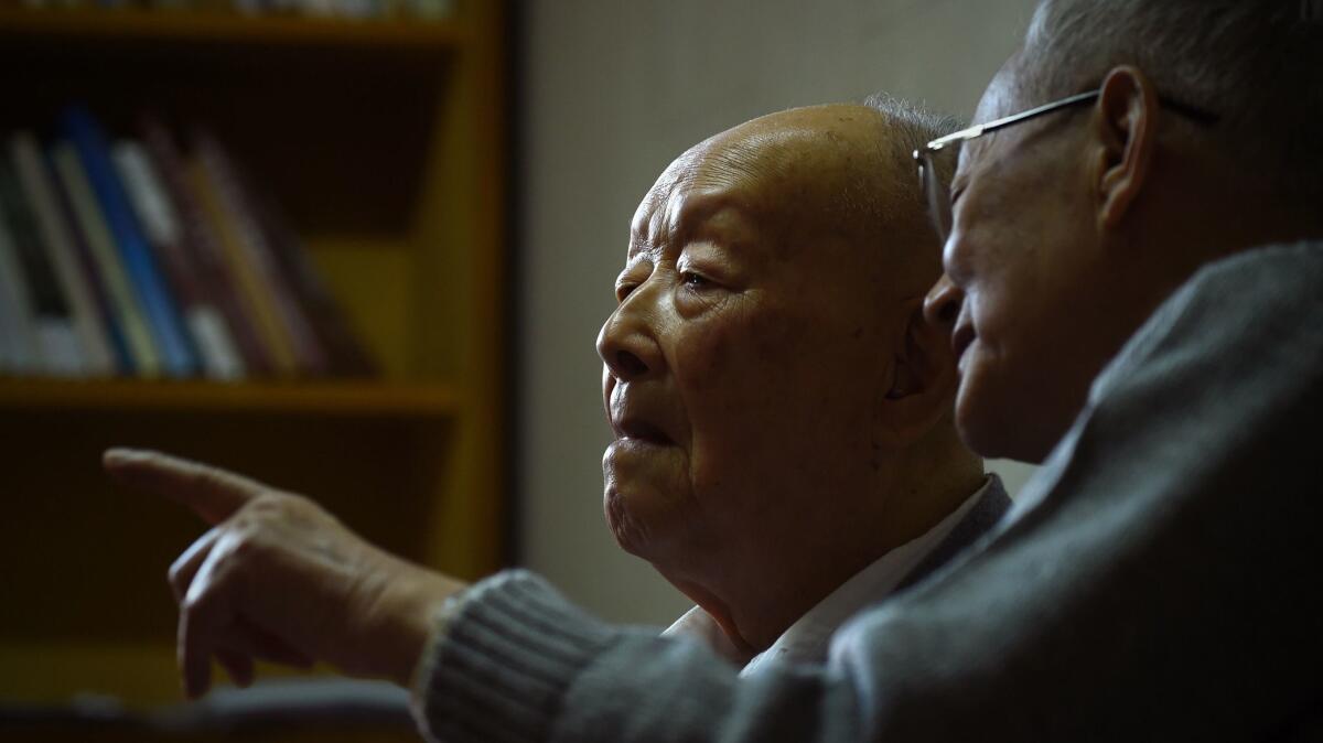 Zhou Youguang, left, talks with his son Zhou Xiaoping at his home in Beijing in 2015.