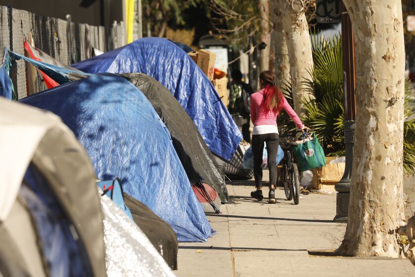 LOS ANGELES, CA - NOVEMBER 15: Encampments block nearly the entire sidewalk on Spring Street near 1st Street across from LA City Hall. Councilman Kevin de Leon, who supports the new fencing while the street lights are fixed, said that part of Main Street had persistent violations of the Americans With Disabilities Act. Spring Street at 1st Street on Monday, Nov. 15, 2021 in Los Angeles, CA. (Al Seib / Los Angeles Times).