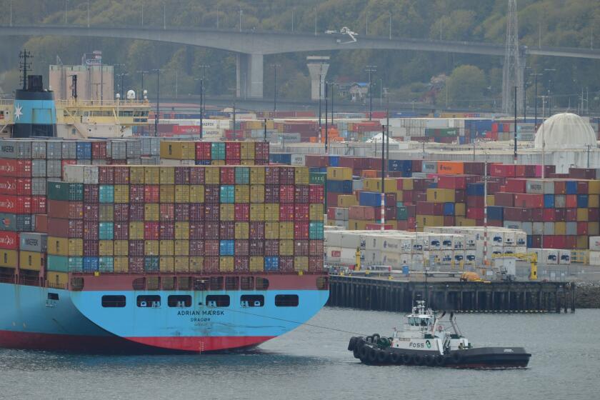 A tugboat pulls a cargo ship away from a Seattle terminal backlogged with containers after a stoppage by dockworkers who said equipment was not disinfected properly to ward off the coronavirus.