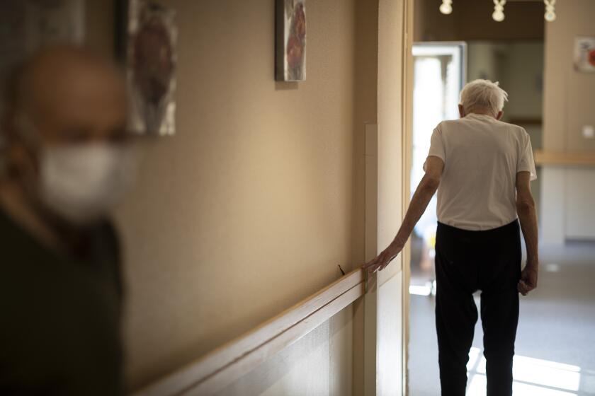 FILE - In this April 16, 2020, file photo, Richard Eberhardt walks along a corridor at a nursing home in Kaysesberg, France. Countries across Europe are struggling amid the coronavirus pandemic with the dilemma of leaving the elderly and others near death in enforced solitude or whether to allow some personal contact with relatives. At nursing homes, everything is done to keep out visitors who might be infected, and family members are almost always banned from coming to see their loved ones. (AP Photo/Jean-Francois Badias, File)
