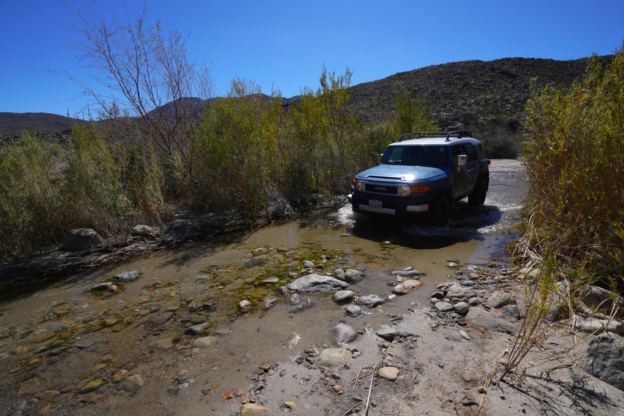 Robert Logan and his wife, Anne, from Orange navigate their vehicle across one of the water streams