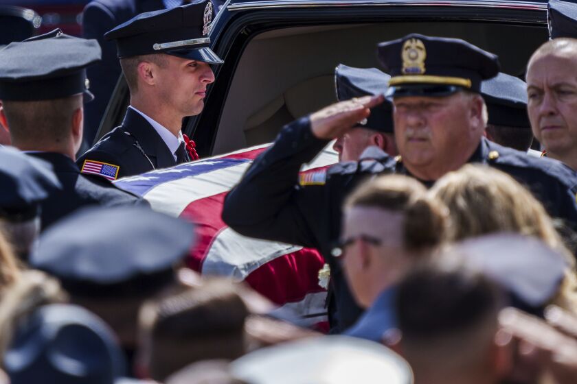 Officers salute the casket of Officer Seara Burton during funeral services Monday, Sept. 26, 2022, inside Richmond High School in Richmond, Ind. Burton was shot and killed in the line of duty. (Mykal McEldowney/The Indianapolis Star via AP)
