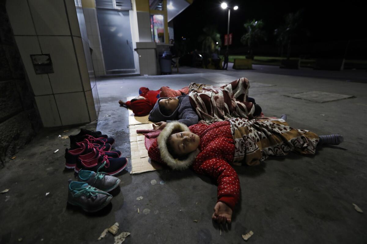 SAN PEDRO SULA, HONDURAS--NOV.7, 2018--The children of Yong Yobay Rodriguez, 36, all under the age of 8, sleep as they wait for a bus in San Pedro Sula, to begin their journey to the United States with their father. Yosmary Dariana Rodriguez, age 6, sleeps next to her brothers and sisters on the ground at the but station in San Pedro Sula. Their mother had gone to the U.S. three months earlier with their youngest sibling, a baby, and was living in Baltimore, Maryland. Rodriguez acknowledges that he was partly leaving because there was no work. He had started working in construction at 12-years-old. Many Hondurans want to leave their country due to high unemployment and lack of opportunity. The economy has continued to get worse under the current administration. (Carolyn Cole/Los Angeles Times)