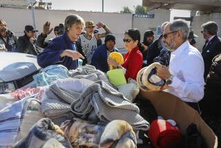 Deacon Jim Vargas (right), president and CEO , Father Joe's Villages and Nancy Sasaki (left), president and CEO, United Way of San Diego County (both wearing sunglasses) hand out blankets at the Neil Good Day Center in downtown on March 5, 2020 in San Diego, California.