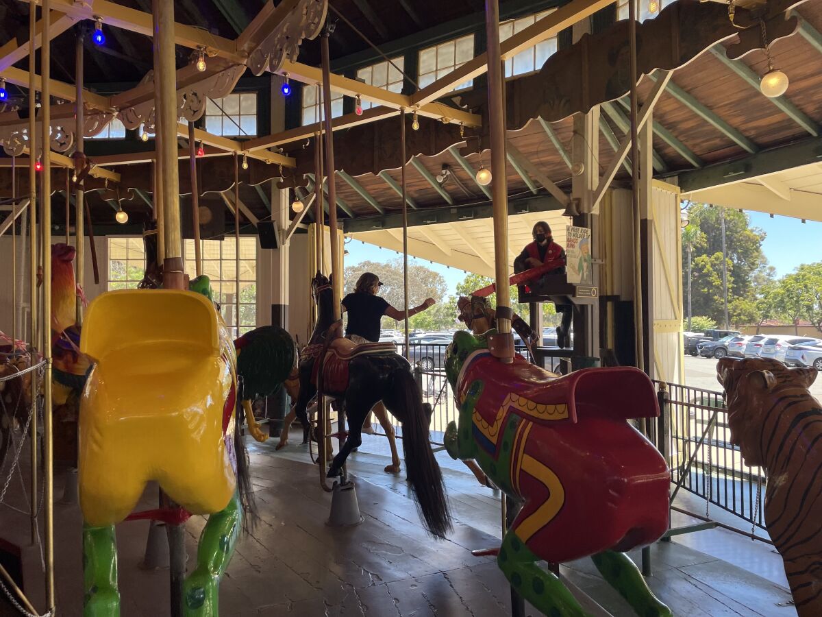 Park visitor Dianna Ahumada retrieves the brass ring, earning a free ride, as she rides the Balboa Park Carousel. 