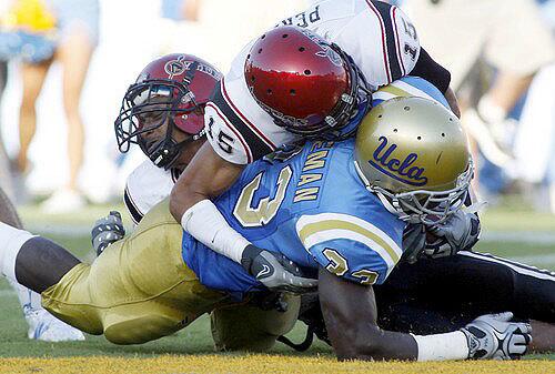 UCLA tailback Derrick Coleman bowls over a pair of San Diego State defenders to finish off a touchdown run in the second quarter Saturday.
