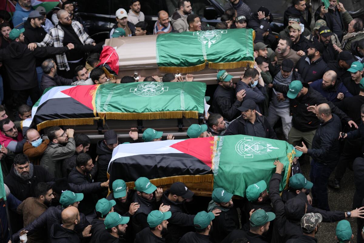 Flag-draped caskets of three Hamas members held aloft by mourners