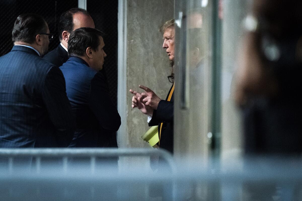 Donald Trump speaks with attorney Todd Blanche and staff outside a courtroom.