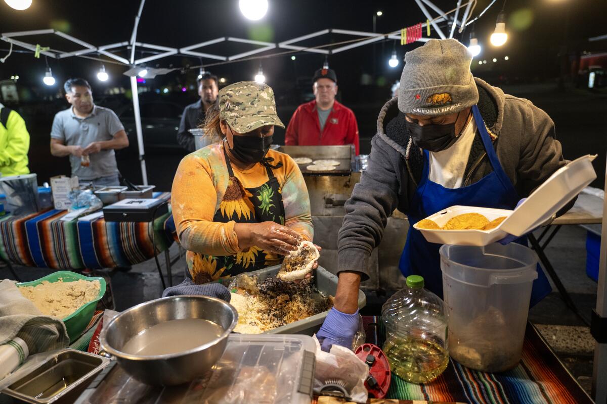 Street vendors make homemade pupusas at their food stand in Fontana last December.