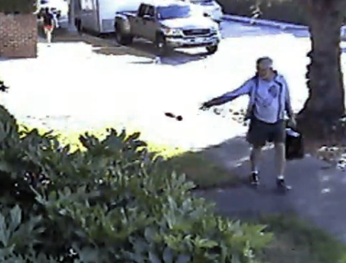In this June 7 image from a security video provided by Philip Lao, Dennis Kneier, the mayor of San Marino, Calif., tosses a bag of dog waste onto the property of his neighbor, Philip Lao, in San Marino.