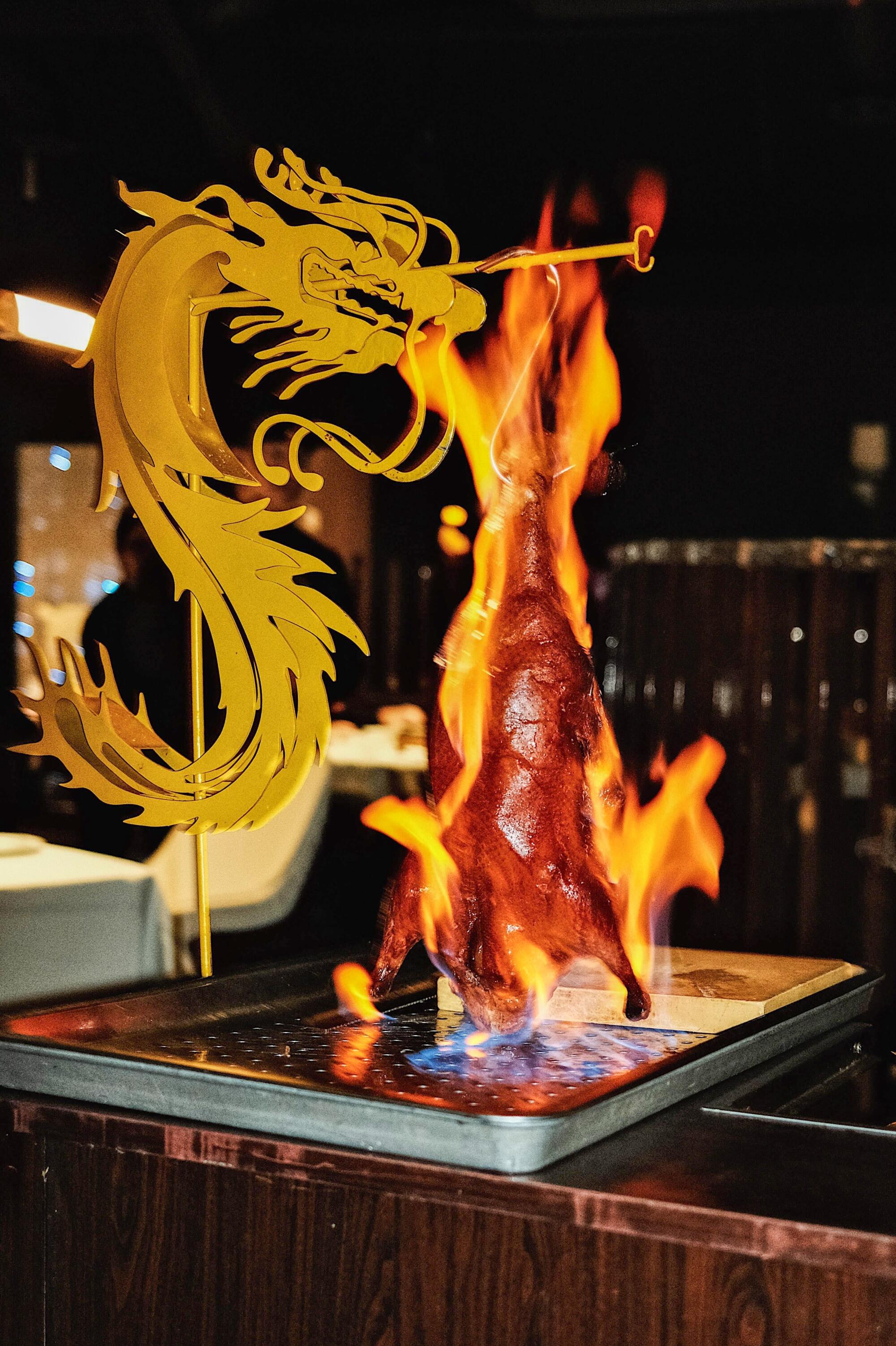 The roast duck arrives at the table, theatrically set ablaze.