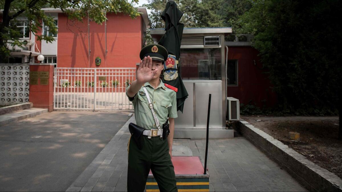 A paramilitary police officer gestures outside the Belgian Embassy in Beijing on June 19, 2019. A Belgian diplomat was expected to travel to China's Xinjiang region to confirm the whereabouts of a Uighur family that was escorted from the embassy by police in May.