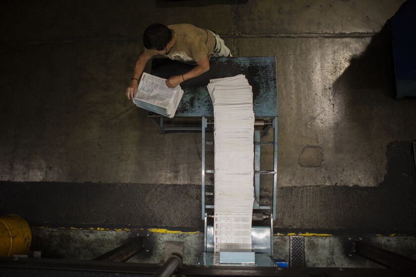 A worker at the elPeriodico newspaper's printing press stacks freshly printed newspapers before they are packed for distribution in Guatemala City on September 6, 2022.