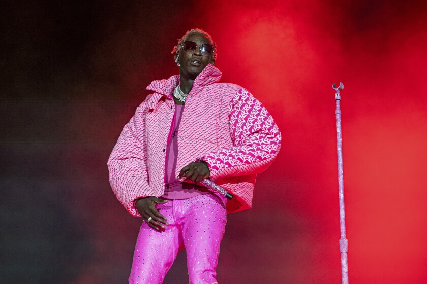 A rapper in a pink outfit performs onstage