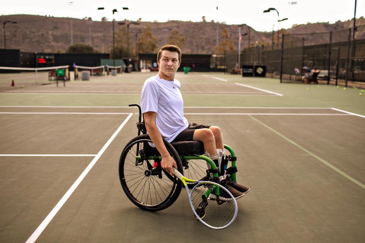Landon Sachs looks on over his shoulder while in a wheelchair on a tennis court.